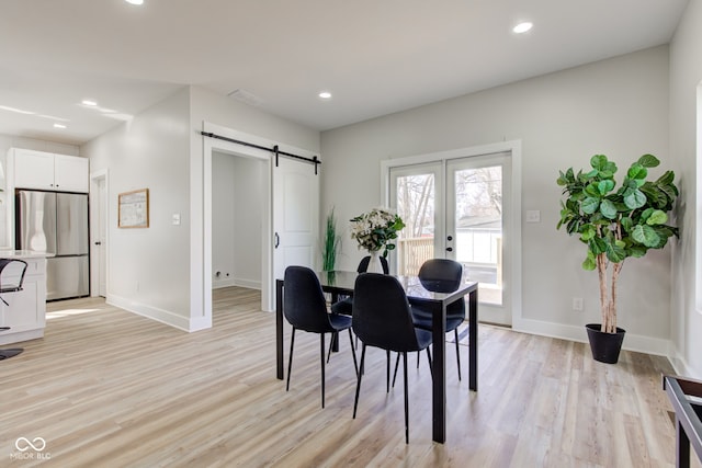 dining room with light wood-style floors, a barn door, baseboards, and recessed lighting