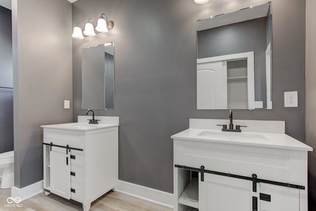 bathroom with baseboards, two vanities, and a sink