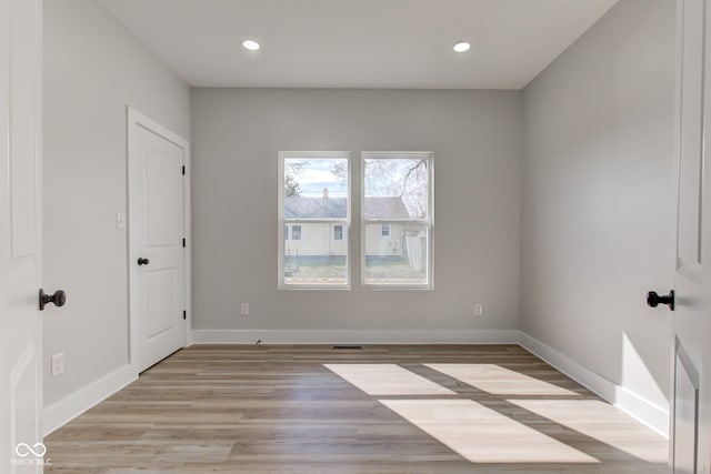 spare room featuring light wood-style floors, recessed lighting, visible vents, and baseboards