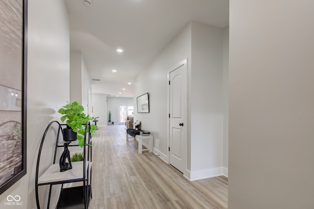 hall featuring light wood-style flooring, visible vents, baseboards, and recessed lighting