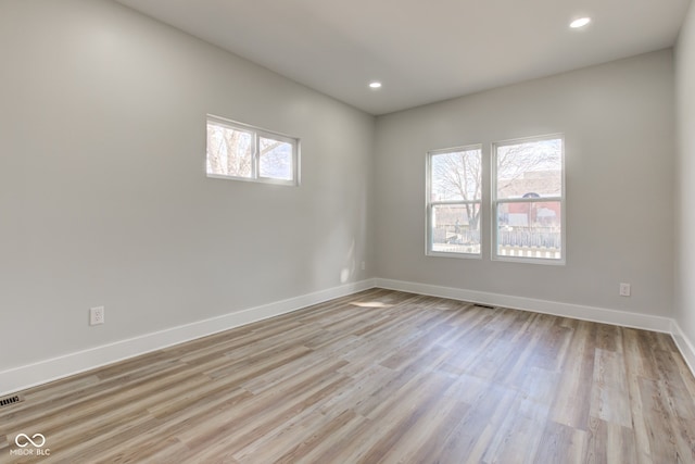 empty room featuring light wood-style floors, recessed lighting, visible vents, and baseboards