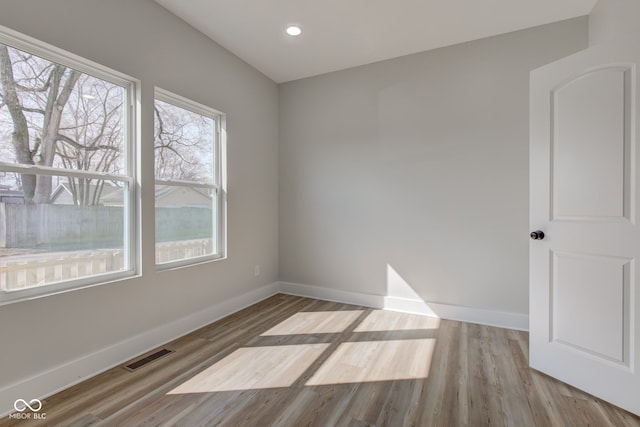 empty room with baseboards, visible vents, wood finished floors, and recessed lighting