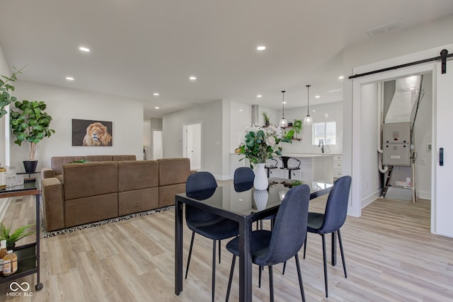 dining area featuring recessed lighting, light wood-style flooring, baseboards, and a barn door