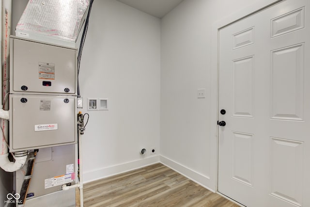 laundry room featuring heating unit, hookup for a washing machine, light wood-style flooring, laundry area, and baseboards