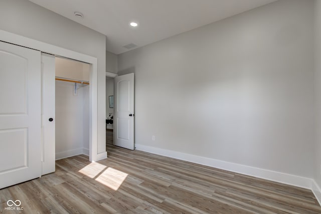 unfurnished bedroom with light wood-type flooring, a closet, baseboards, and recessed lighting