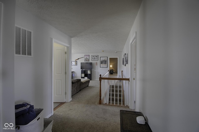 corridor with light colored carpet and a textured ceiling