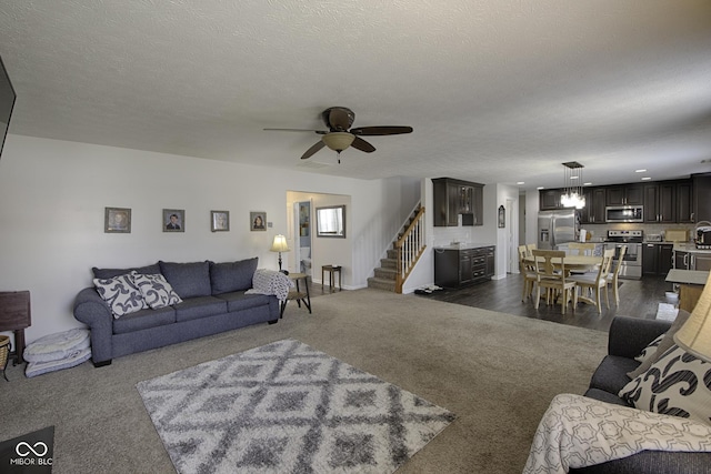 carpeted living room featuring ceiling fan and a textured ceiling