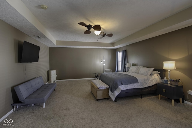 carpeted bedroom featuring ceiling fan, a tray ceiling, and a textured ceiling