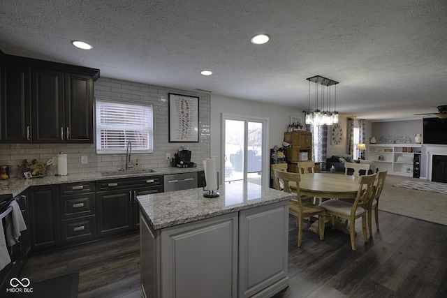 kitchen with dark wood-type flooring, sink, a center island, dishwasher, and pendant lighting