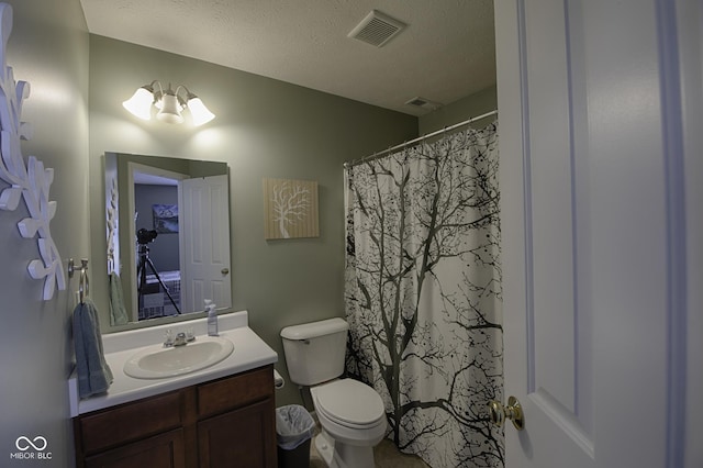 bathroom with vanity, toilet, and a textured ceiling