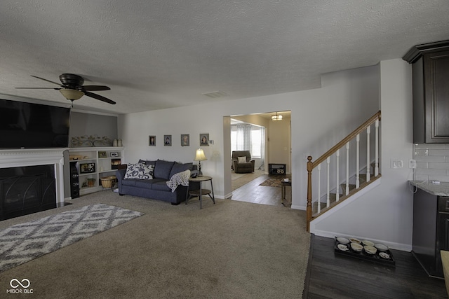 living room with ceiling fan, light carpet, and a textured ceiling