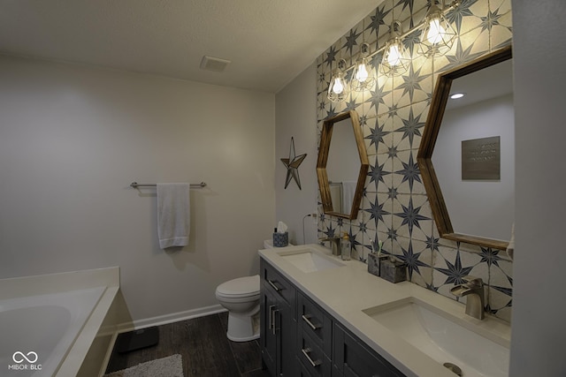 bathroom featuring a tub to relax in, toilet, wood-type flooring, a textured ceiling, and vanity