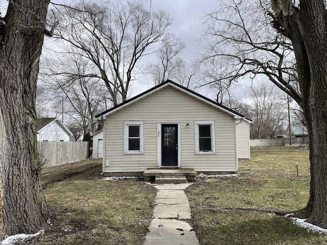 bungalow-style home featuring fence and a front lawn