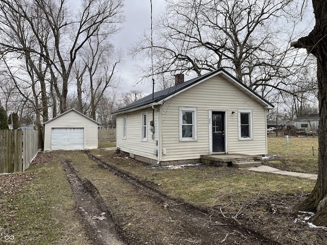 bungalow featuring an outbuilding, a detached garage, fence, driveway, and a chimney