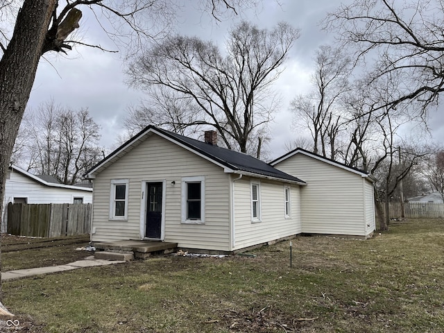 back of house featuring a yard, a chimney, and fence