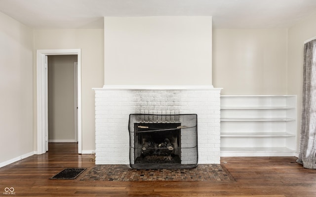 unfurnished living room with dark wood-type flooring and a brick fireplace