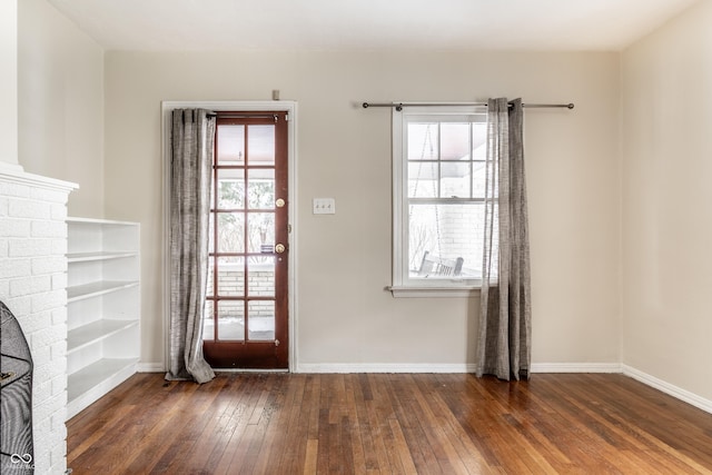 doorway with dark wood-type flooring and a brick fireplace