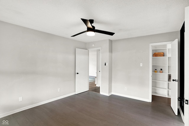 unfurnished bedroom with a textured ceiling, wood finished floors, a ceiling fan, and baseboards