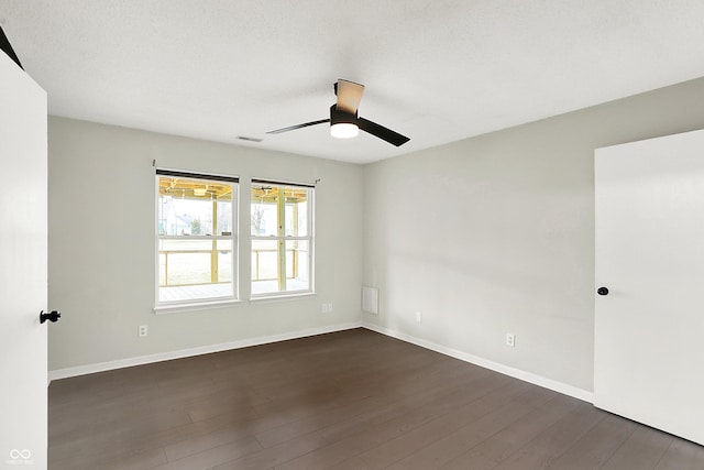 unfurnished room featuring a ceiling fan, dark wood finished floors, visible vents, and baseboards