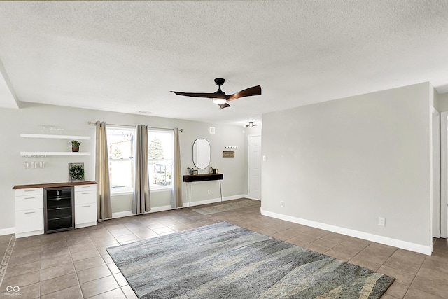 interior space featuring beverage cooler, a textured ceiling, tile patterned flooring, and a ceiling fan