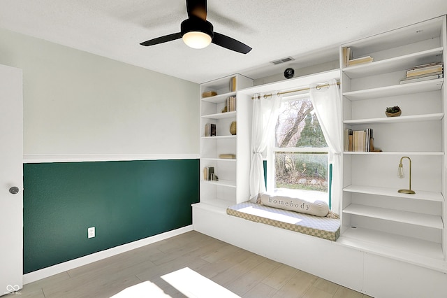 interior space featuring visible vents, ceiling fan, a textured ceiling, wood finished floors, and baseboards