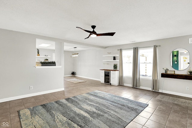 living area with tile patterned flooring, baseboards, and ceiling fan