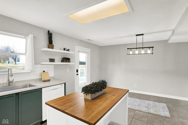 kitchen featuring wooden counters, green cabinets, a sink, plenty of natural light, and dishwasher