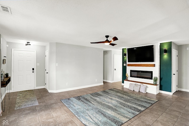 unfurnished living room featuring a large fireplace, visible vents, baseboards, a ceiling fan, and tile patterned floors