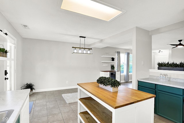 kitchen featuring light tile patterned floors, visible vents, wood counters, beverage cooler, and green cabinetry