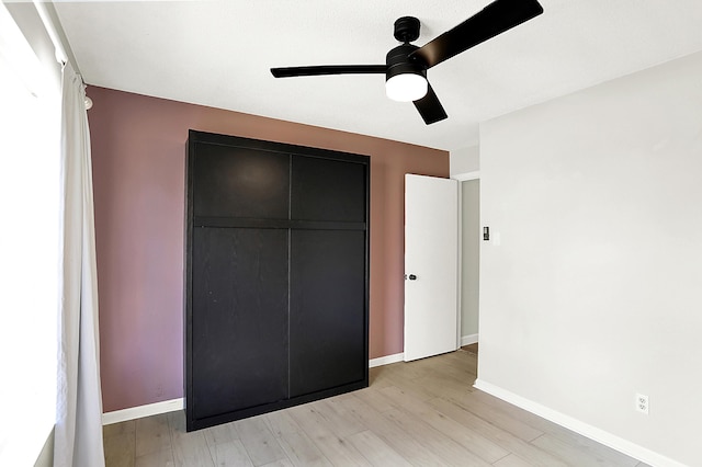 unfurnished bedroom with a ceiling fan, a closet, baseboards, and light wood finished floors