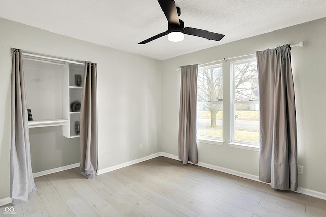 unfurnished bedroom featuring baseboards, a textured ceiling, and light wood-style floors