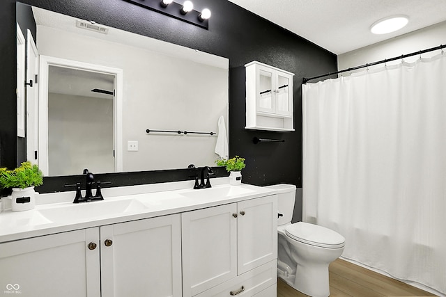 full bath with double vanity, wood finished floors, a sink, and visible vents