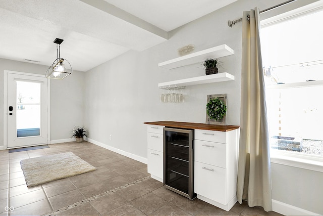 interior space with a dry bar, beverage cooler, baseboards, and a wealth of natural light