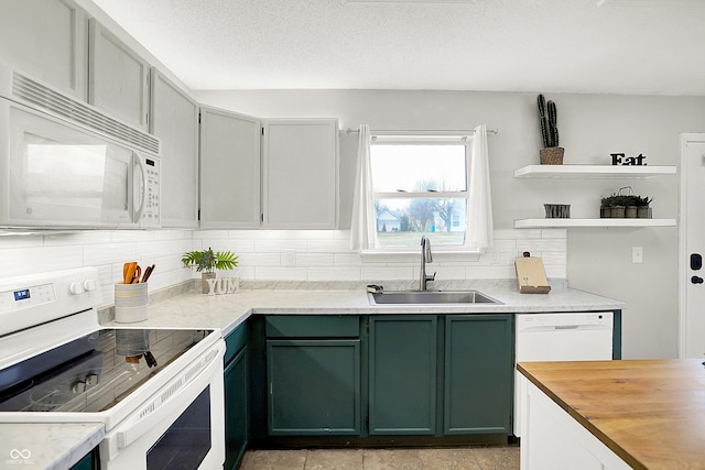 kitchen featuring white appliances, decorative backsplash, green cabinetry, a textured ceiling, and a sink