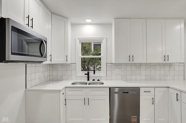 kitchen with white cabinets, light countertops, appliances with stainless steel finishes, and a sink