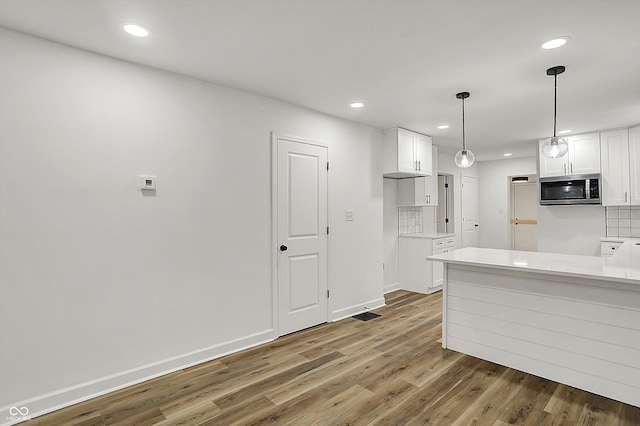 kitchen with recessed lighting, light wood-style floors, stainless steel microwave, and white cabinetry