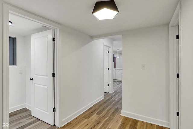 hall featuring light wood-style flooring and baseboards