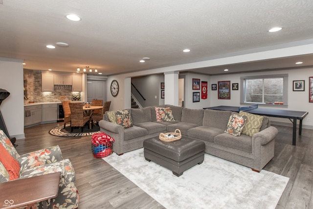 living room featuring beverage cooler, a textured ceiling, wood finished floors, recessed lighting, and stairs