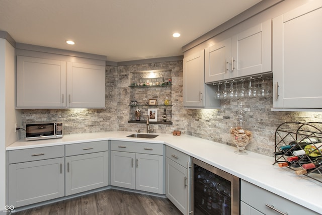 kitchen with wine cooler, gray cabinetry, light countertops, and a sink