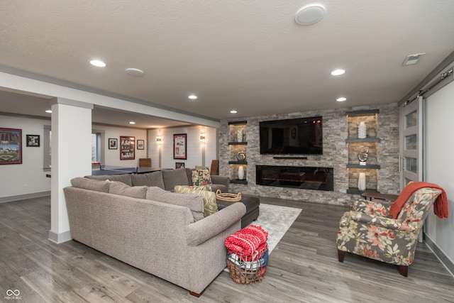 living area with recessed lighting, a fireplace, a textured ceiling, and wood finished floors