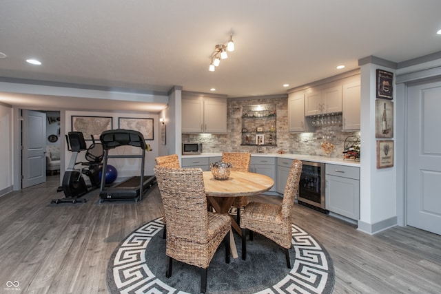 dining room featuring wood finished floors, baseboards, recessed lighting, wine cooler, and a dry bar