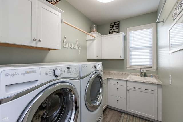 laundry area with cabinet space, independent washer and dryer, dark wood-type flooring, and a sink