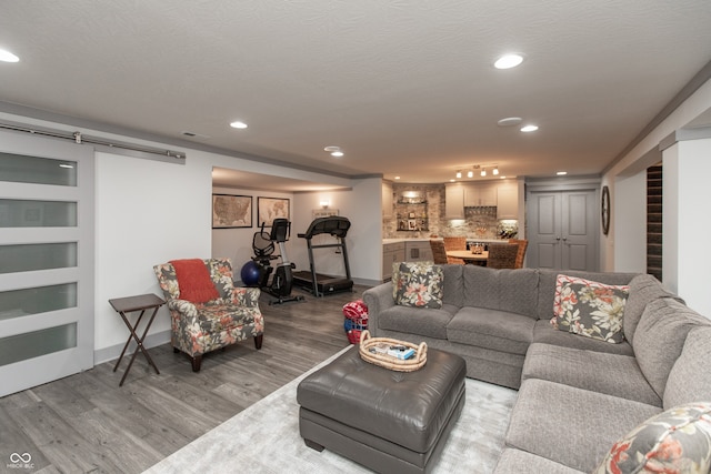 living area featuring visible vents, a textured ceiling, wood finished floors, recessed lighting, and a barn door