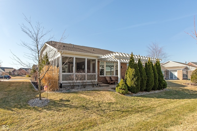 back of house featuring brick siding, a lawn, a pergola, and a sunroom