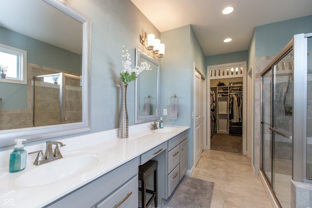 full bath featuring a sink, a walk in closet, a stall shower, and double vanity