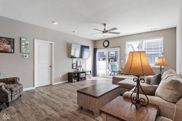 living room with a textured ceiling, wood finished floors, a ceiling fan, and baseboards