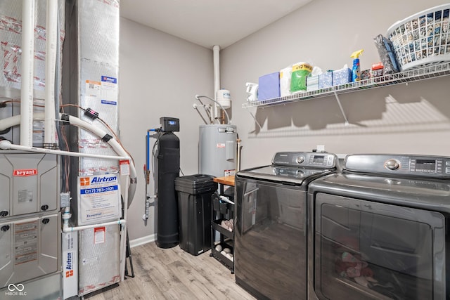 clothes washing area featuring light wood-type flooring, laundry area, electric water heater, and independent washer and dryer