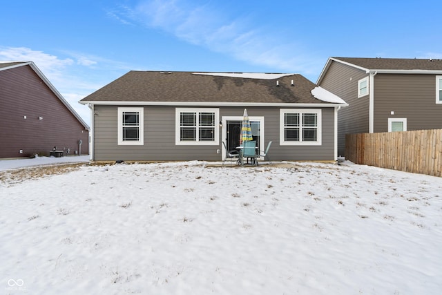 snow covered property with a shingled roof