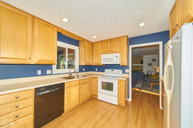 kitchen featuring a textured ceiling, white appliances, a sink, light countertops, and light wood-type flooring