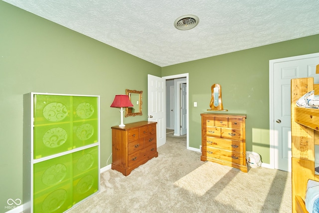 bedroom featuring baseboards, visible vents, light carpet, and a textured ceiling